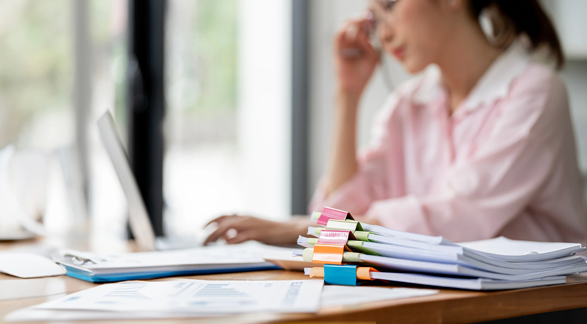 Digitalisierung in der Verwaltung - Frau mit ausgedruckten Dokumenten am Computer